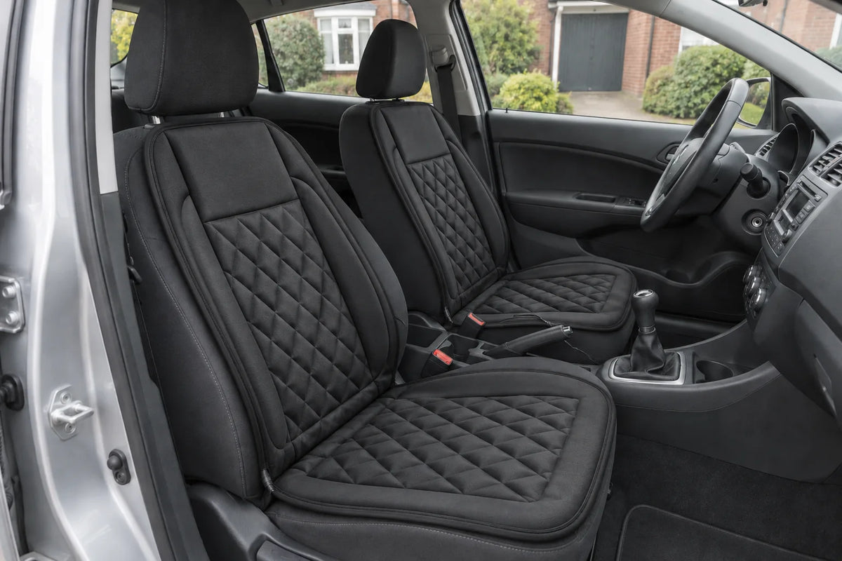 Illustrative view of two black Heat Seat covers fitted to the front seats of a right-hand-drive car